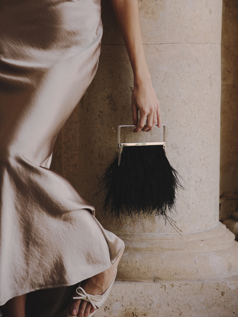 Clutch bag with feather detailing and a metal handle