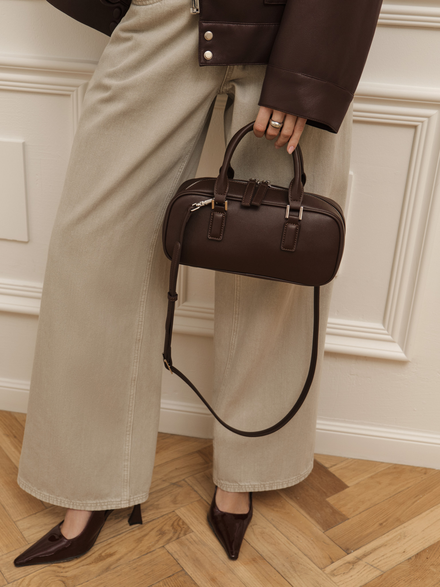 Rigid-shaped bag with short handles and a strap