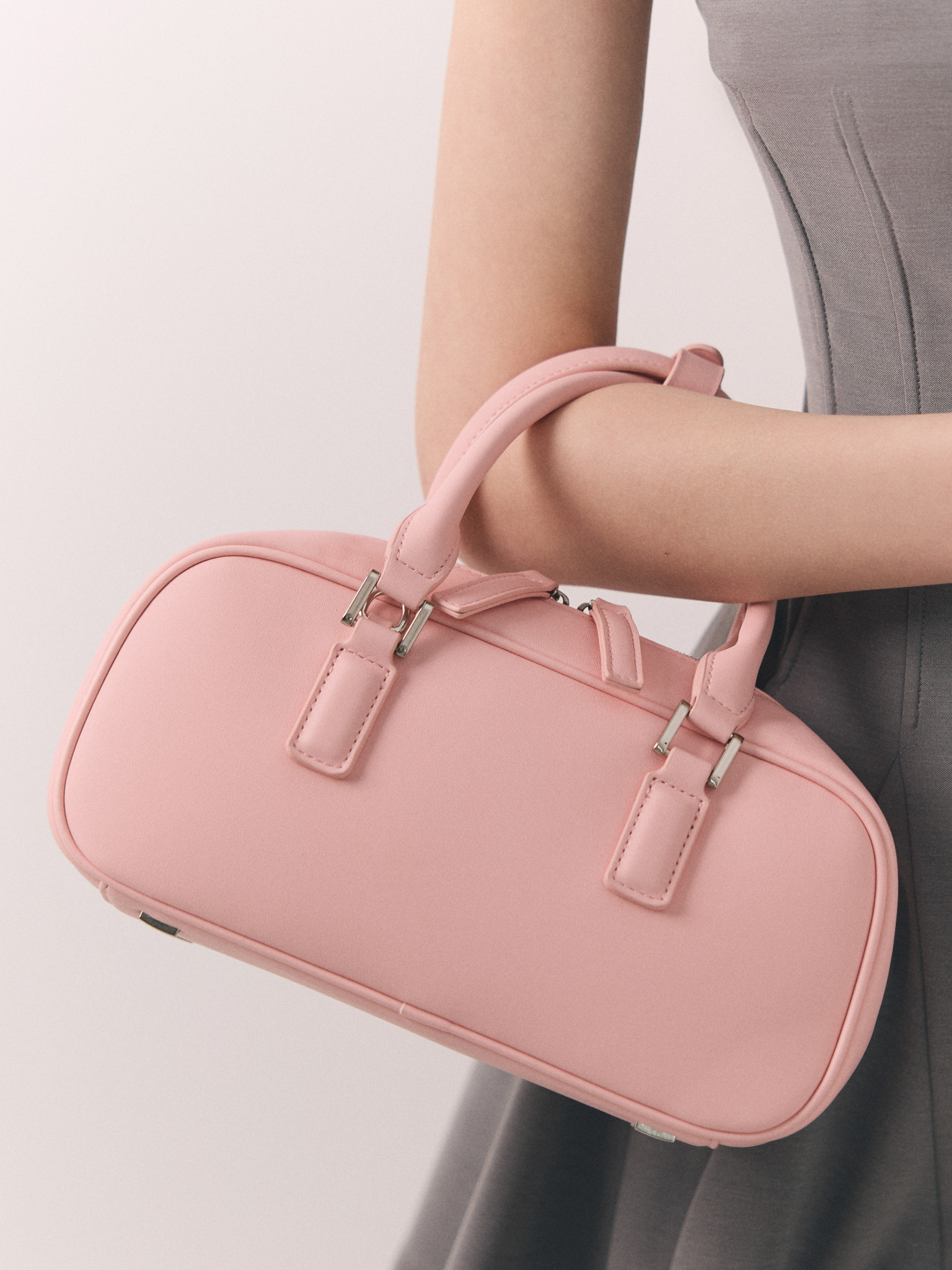 Rigid-shaped bag with short handles and a strap